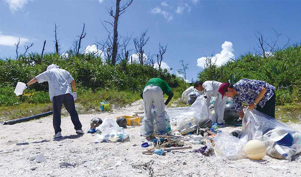 浜辺にてゴミ拾いを行う人たち。
