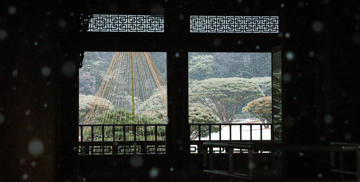 [写真]新宿御苑の旧御凉亭から見える冬の形式です。窓から見える木々や地面には雪が積もっています。