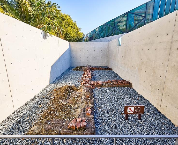 [写真]旧温室の遺構。 温室の最東端にあたる基礎部分で、基礎石の上に切石や煉瓦が一部積まれた状態で保存されています。