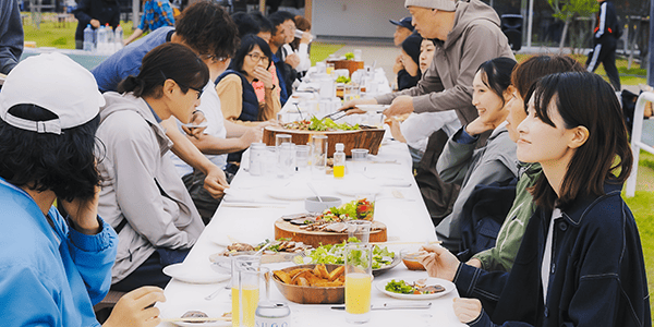 画像：地域の食材やプロダクトを囲みながら、参加者が一つのテーブルで楽しそうに談笑している様子