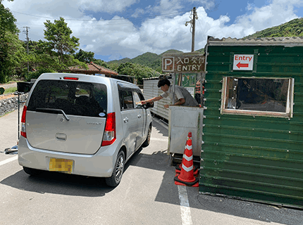 画像：パークキーパー補佐の高校生が駐車場入り口で接客をしている様子