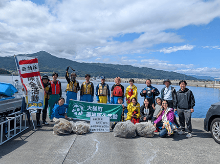  画像：海辺でメンバー揃って活動報告を兼ねた集合写真撮影