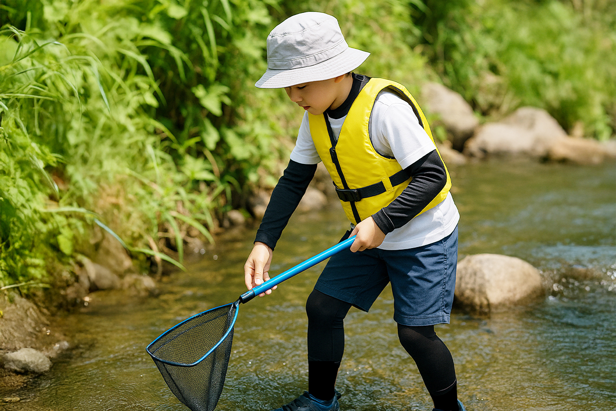 ガサガサをしているこども、黄色ライフジャケット着用
